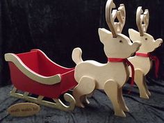 two wooden reindeer pulling a sleigh on a black background