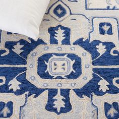 a blue and white rug with an intricate design on the bottom, next to a pillow