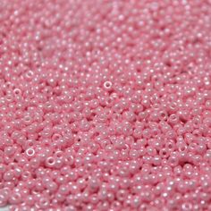 pink seed beads are shown on a white surface