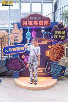 a woman standing in front of a sign with neon signs on it's sides