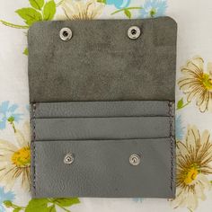 a wallet with two buttons on it sitting on top of a flowered table cloth