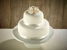 a three tiered white wedding cake sitting on top of a table