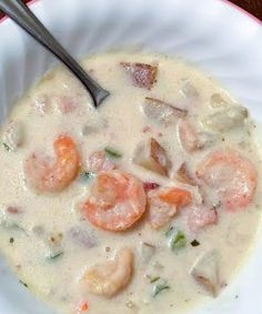 a white bowl filled with shrimp and chowdery on top of a red table