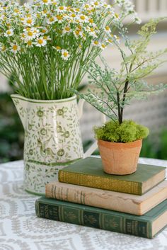 two books are stacked on top of each other near a vase with flowers in it