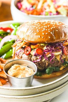 a hamburger with lettuce, tomato and onion on it next to some fries