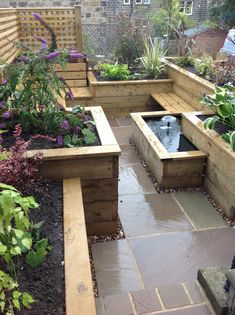 an outdoor garden with wooden planters and water feature in the center, surrounded by brick walls