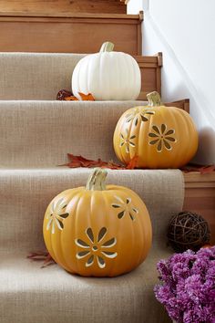 two pumpkins sitting on some steps with fall leaves