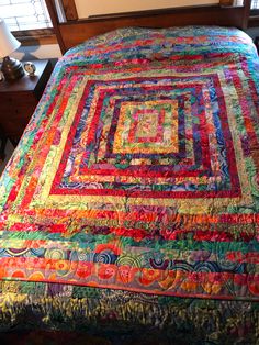 a bed with a colorful quilt on it in a room next to a lamp and window