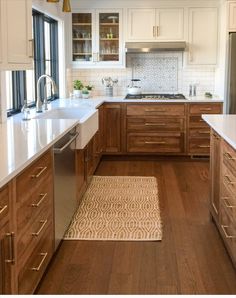 a kitchen with wooden cabinets and white counter tops, along with a rug on the floor