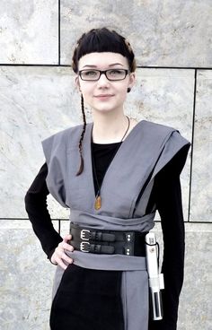 a woman standing in front of a stone wall wearing glasses and a star wars costume