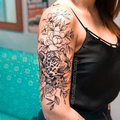 a woman with a black and white flower tattoo on her arm, wearing a black tank top