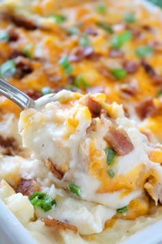 a spoonful of mashed potatoes with bacon and green onions in a casserole dish