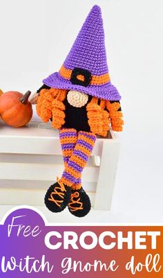 a crocheted witch doll sitting on top of a white table next to a pumpkin