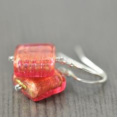 two pieces of red glass sitting on top of each other next to silver ear wires