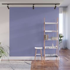 an empty room with a purple wall and wooden flooring in the corner, there is a book shelf on one side