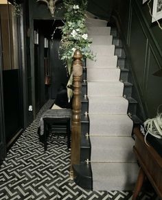 the stairs are decorated with greenery and gold trimmings, along with a black chair