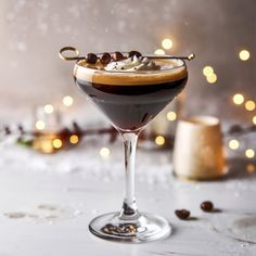 a glass filled with liquid sitting on top of a table next to christmas lights and decorations