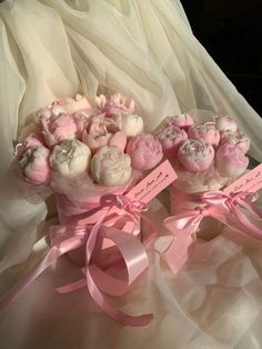 two bouquets of pink and white candies with ribbons on the bottom are sitting next to each other