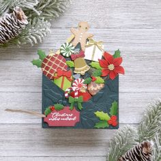 a christmas card with some decorations and pine cones on the table next to it is an ornament