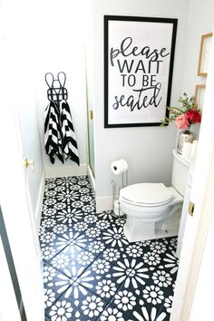 a white toilet sitting in a bathroom next to a black and white tiled flooring