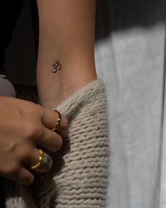 a person with a small tattoo on their left arm and the word om written below it