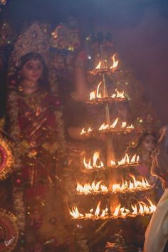 a woman standing next to a man in front of a fire lit christmas tree on display