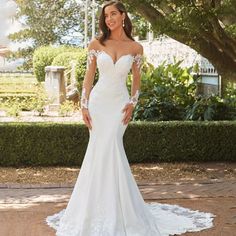 a woman in a white wedding dress posing for the camera with her hands on her hips