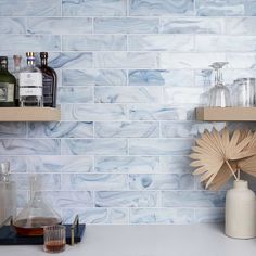 a shelf with bottles and glasses on it in a room that has blue marble tiles