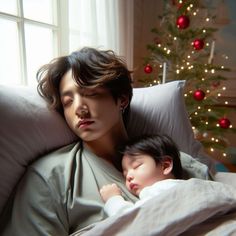 a woman and child sleeping on a bed in front of a christmas tree with lights