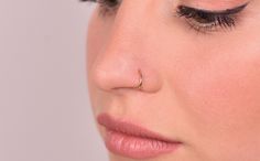 a close up of a woman's face with her nose piercing