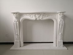 a white marble fireplace surround in an empty room