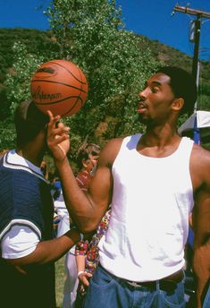 a man holding a basketball in his right hand while standing next to another man on the other side