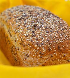 a loaf of bread sitting on top of a yellow cloth covered in sesame seed sprinkles