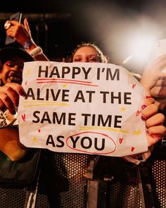 a woman holding up a sign that says happy i'm alive at the same time as you