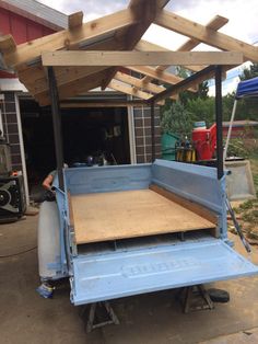 the back end of a blue truck with wood planks on it's sides