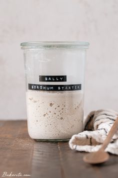 a glass jar filled with food sitting on top of a wooden table next to a towel