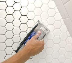 a person using a sponge to clean a bathroom tile