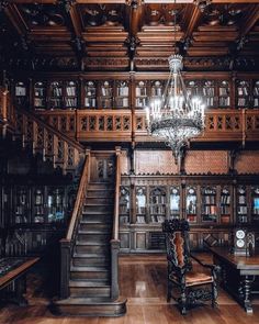 a large wooden room with many bookshelves and a chandelier hanging from the ceiling