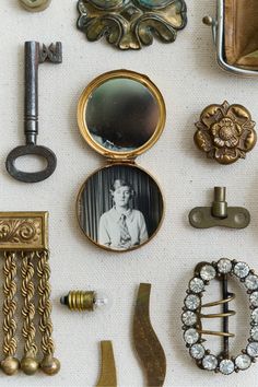 an assortment of antique and vintage items are displayed on a white tablecloth with gold trimmings