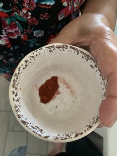 a person holding a white bowl with brown stuff in it