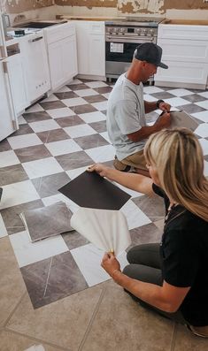 two people sitting on the floor in a kitchen working on some tile designs with their hands