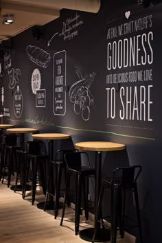 there are many stools in front of the black wall with writing on it that says goodness to share