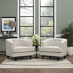 two white chairs sitting next to each other on top of a rug in front of windows