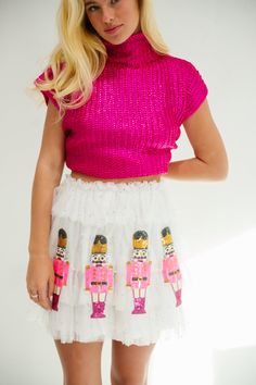 Add a touch of whimsy with our Nutcracker Ruffle Skirt. The white ruffle skirt is adorned with pearls and features an elastic waist for a comfortable fit. Stand out with playful pink sequin nutcracker patches. (Don't be a nutcracker, add some flair!) All orders are currently shipping within 14 business days. To receive item quicker, expedited shipping is available at checkout. **All Christmas orders must be placed with expedited shipping to guarantee delivery by Dec. 24 if placed after Dec. 10. Pastel Christmas Outfit, Playful White Skirt With Ruffles, Nutcracker Inspired Outfit, Pink Festive Skirt For Spring, Festive Pink Skirt For Spring Season, Festive Pink Skirt For Spring, Ruffled Tiered Skirt For Festive Occasions, Festive Tiered Ruffled Skirt, Festive Tiered Ruffle Skirt