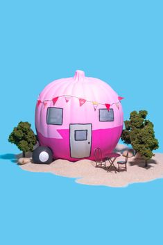 an inflatable pink trailer is parked on the beach next to trees and chairs