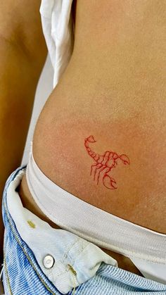 a woman's stomach with a small red tattoo on her lower back and side