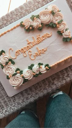 there is a cake that says congratulations cake on the table next to someone's feet