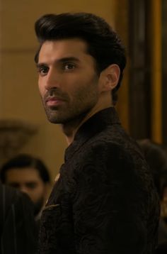 a man standing in front of a group of people wearing black clothing and looking at the camera