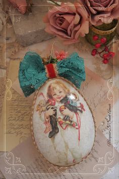 an ornament with a bow on it sitting next to roses and writing paper