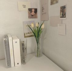 a vase filled with white flowers sitting on top of a table next to two books